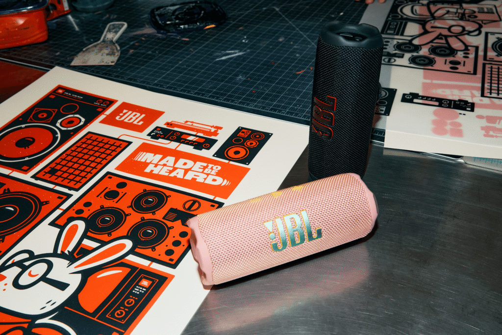 Persona escuchando música con la bocina JBL Go 4 sobre una mesa junto a una bebida fría