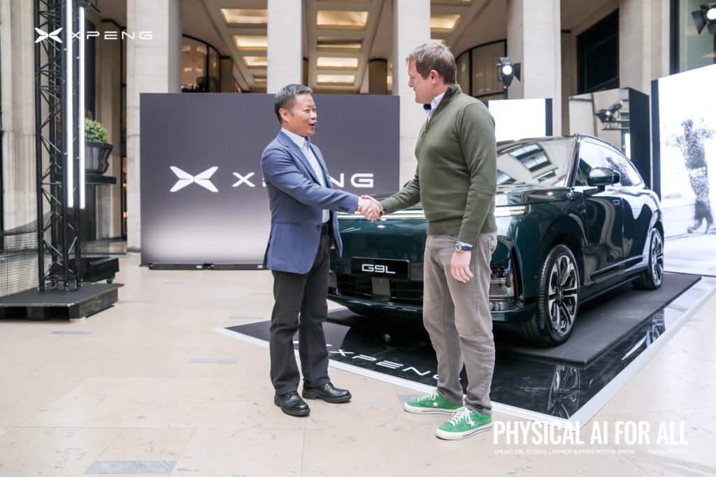 He Xiaopeng saluda a otra persona mientras un automóvil de XPENG permanece detrás de ellos