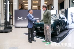 He Xiaopeng saluda a otra persona mientras un automóvil de XPENG permanece detrás de ellos